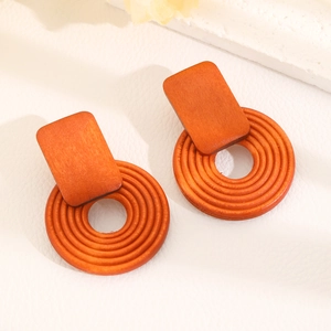 Macro detail of terracotta geometric wooden earrings with textured circular drop