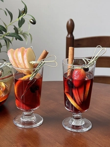 Close-up of festive mulled wine in tall glasses with fresh fruit and cinnamon sticks