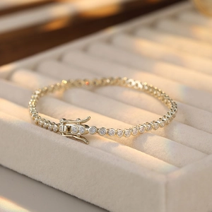 Detail of gold S925 sterling silver tennis bracelet with cubic zirconia on beige velvet