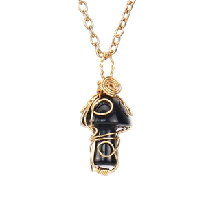 Macro shot of handmade gold wire wrapped mushroom pendant with polished black onyx stone