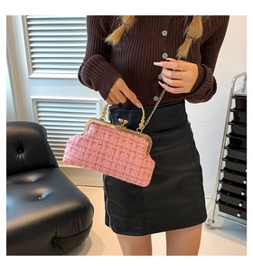 Close-up of pink tweed handbag with gold chain handle held by model in interior setting