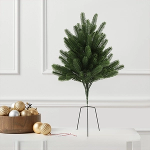 Close-up of a miniature green Christmas tree featuring realistic needles and a black metal stand
