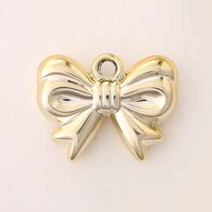 Macro shot of a shiny gold bow pendant for DIY jewelry on a neutral background