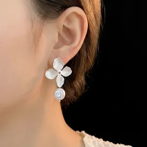 Elegant floral pearl earrings featuring a white four-petal flower and baroque pearl drop