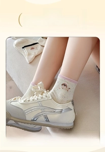 Detailed close-up of cream knit socks with cute puppy embroidery and pink striped cuffs