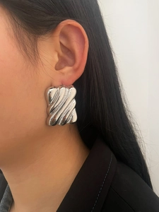 Close-up of a silver large square metallic earring with ripple texture on female model