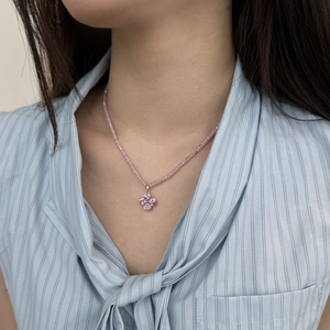 Detail of pink clover pendant necklace with luxury crystal beads worn by a model