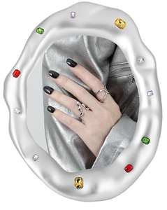 Artistic reflection in silver frame showing wavy and crisscross silver rings on a hand