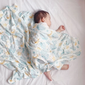 Macro detail of soft muslin bamboo swaddle blanket with blue clouds and yellow moon