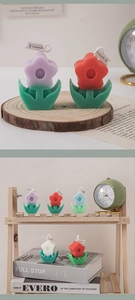 Detailed view of flower-shaped scented candles in purple and red with green leaf bases