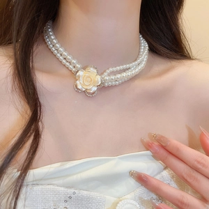 Close-up of double-layer pearl necklace featuring a diamond-encrusted cream rose pendant