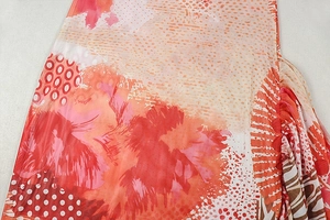 Close-up of abstract print fabric featuring vibrant warm tones and side ruching detail