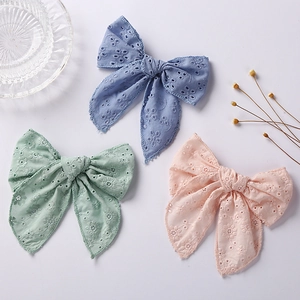 Detailed macro view of embroidered cotton bow hair clips in pastel blue, mint, and pink colors
