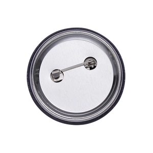 Detailed back view of round tinplate brooch showing silver metal pin and textured surface