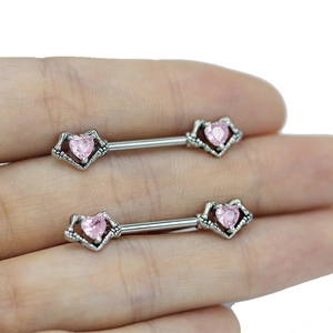 Macro shot of silver nipple rings featuring skull claws holding pink heart gemstones