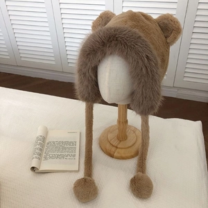 Close-up of brown plush bear ear hat with soft faux fur texture and pom-pom drawstrings