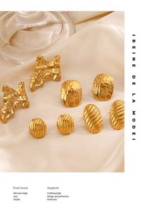 Detailed macro view of vintage golden textured earrings on elegant beige silk fabric