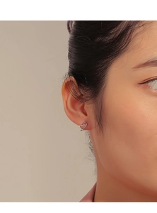 Close-up of minimalist silver heart studs on model to show size and polished finish