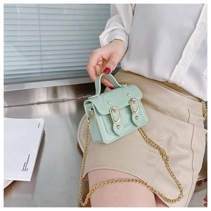 Detail of mint green mini satchel featuring a gold chain strap and magnetic buckle