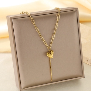 Vue détaillée du pendentif cœur doré avec pompon sur une chaîne trombone chic