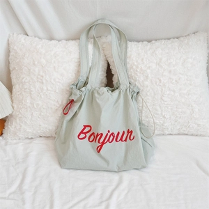 Detail of light green canvas drawstring tote with red Bonjour print and soft texture