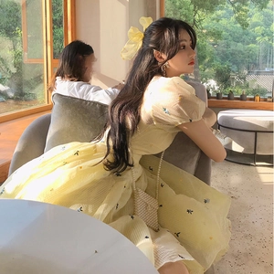 Detail of yellow tulle princess dress with delicate floral embroidery and pearl bag