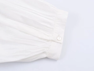 Detailed macro view of white poplin shirt cuff with button and delicate pleat texture