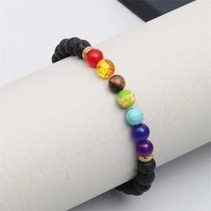 Détail de bracelet chakra en pierre de lave et œil de tigre sur support blanc