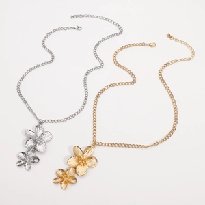 Detail of overlapping metal flower pendants in gold and silver finish with lobster clasp