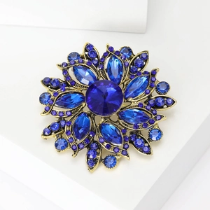 Macro detail of vintage flower brooch featuring deep blue crystals on antique gold metal