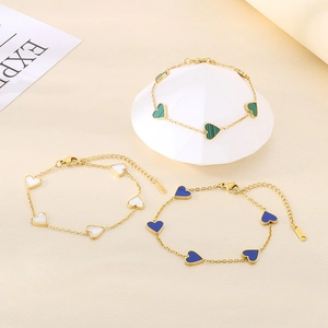 Detailed view of three gold titanium heart bracelets with malachite and shell inlays