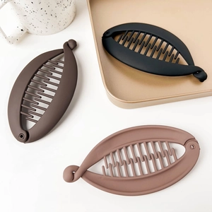 Close-up of matte banana clips in black and brown shades on a gold tray background