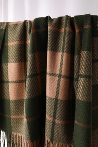 Detailed macro view showing soft plaid cashmere-like fabric texture and fringe tassels