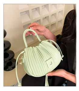 Detail of light green pleated bucket bag showing vertical folds and square buckle detail