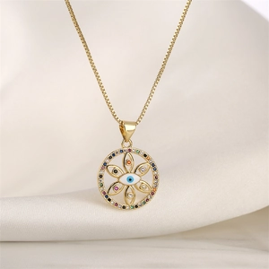 Close-up of golden evil eye heart pendant with colorful stones on white silk fabric