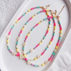 Close-up of three Bohemian beaded necklaces with daisy charms in a ceramic tray