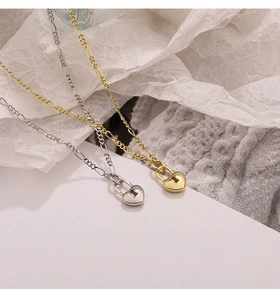 Detail of silver and gold heart lock pendants on Figaro chains for women