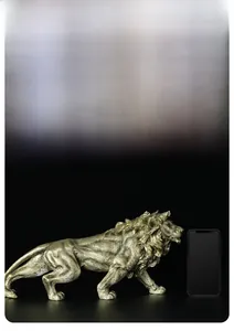 Golden lion statue detail showing muscle lines with a phone for size reference