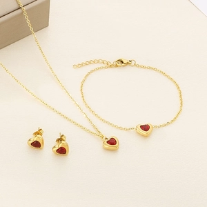 Parure de bijoux en acier inoxydable 18k avec pierres cœurs rouges sur fond beige texturé