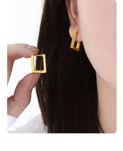 Close-up of geometric gold rectangular earrings with a polished finish on earlobe