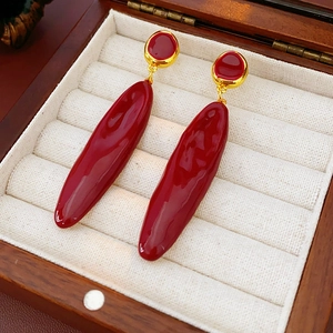 Vue macro de boucles d'oreilles pendantes bordeaux dans un écrin à bijoux en bois élégant