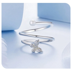 Detailed macro of S925 silver ring featuring a pearl and zircon butterfly on light blue background