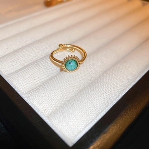 Macro detail of a gold plated dragon ring with a round green turquoise stone in a gift box