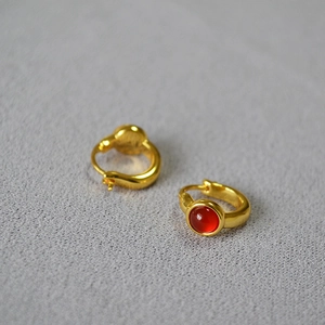 Macro shot of minimalist gold brass earrings with round red agate stone inlay