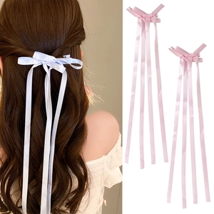 Pink and white bow hair clips with long ribbons displayed on a model and as product shots