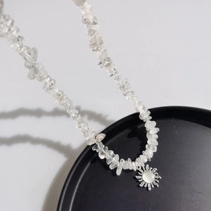 Irregular crystal bead necklace with silver sunflower pendant on black tray