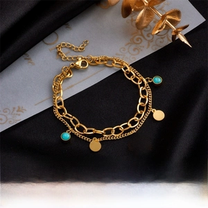 Detail of double-layer gold chain bracelet with evil eye and turquoise charms on black silk
