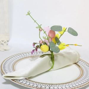 Close-up of Easter napkin ring with speckled eggs, yellow flowers and eucalyptus leaves