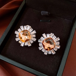 Macro shot of vintage sunburst earrings with amber central crystal on dark brown velvet