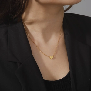 Minimalist gold heart necklace with letter A pendant on delicate chain worn by model